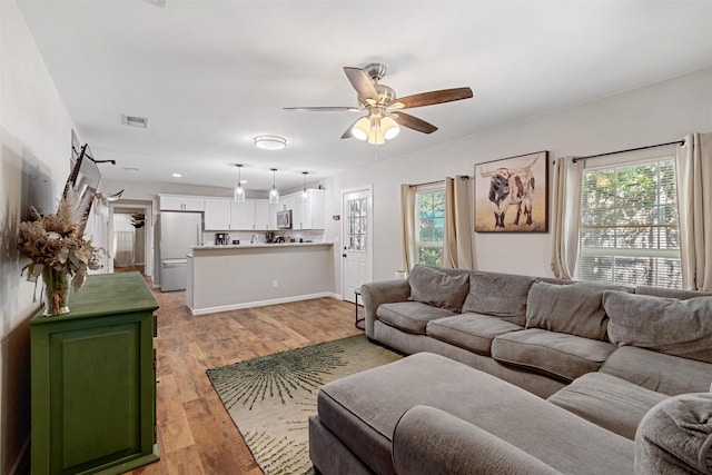 living room featuring a wealth of natural light, ceiling fan, and light hardwood / wood-style flooring