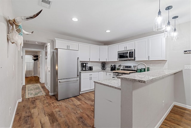 kitchen featuring kitchen peninsula, tasteful backsplash, stainless steel appliances, hardwood / wood-style flooring, and white cabinets