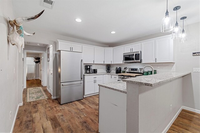 kitchen with tasteful backsplash, kitchen peninsula, white cabinets, and appliances with stainless steel finishes