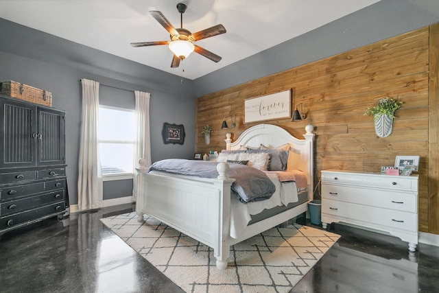 bedroom with ceiling fan and wood walls