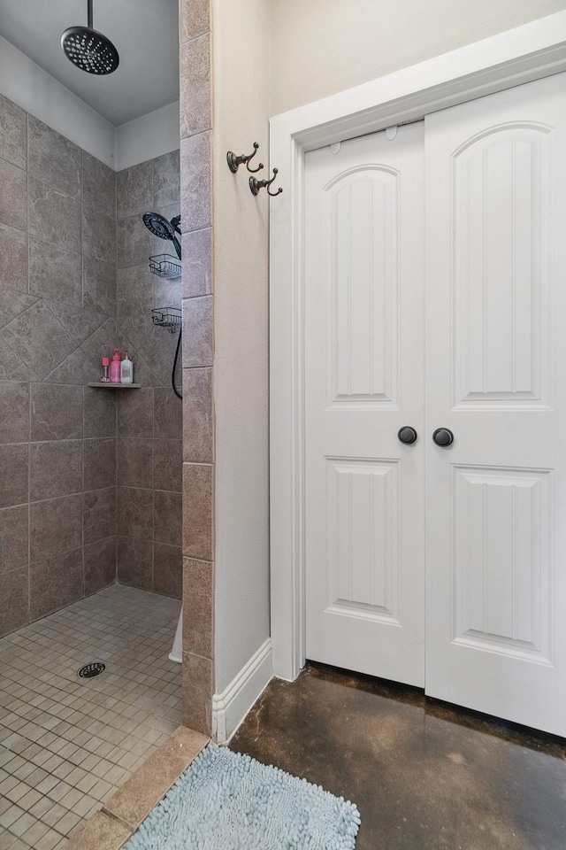 bathroom with a tile shower and concrete flooring