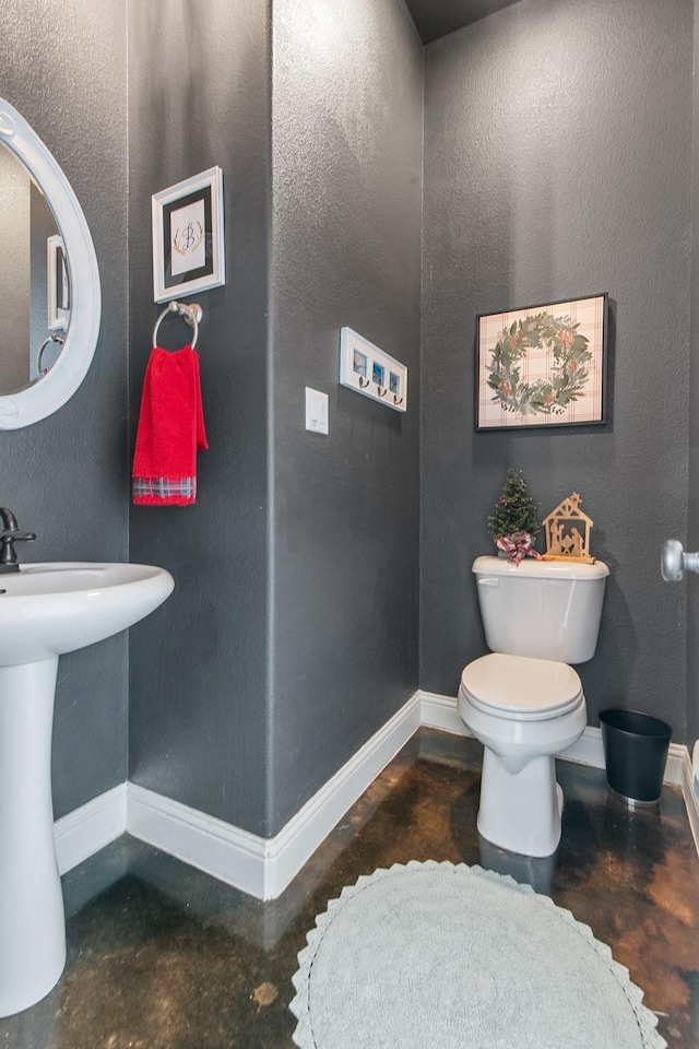 bathroom featuring toilet, sink, and concrete floors