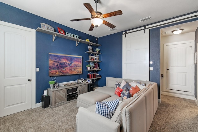 carpeted living room with a barn door and ceiling fan