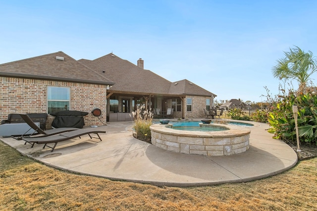 exterior space featuring an in ground hot tub and a patio area