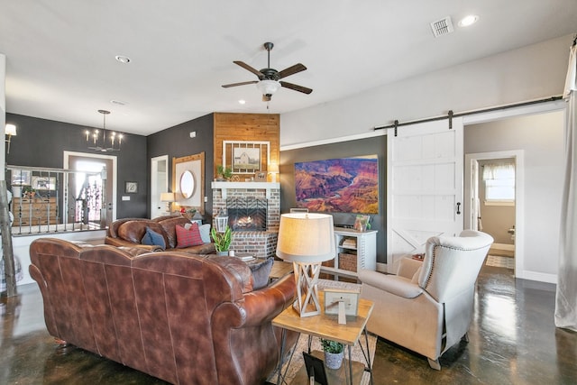 living room with a barn door, a fireplace, and ceiling fan with notable chandelier