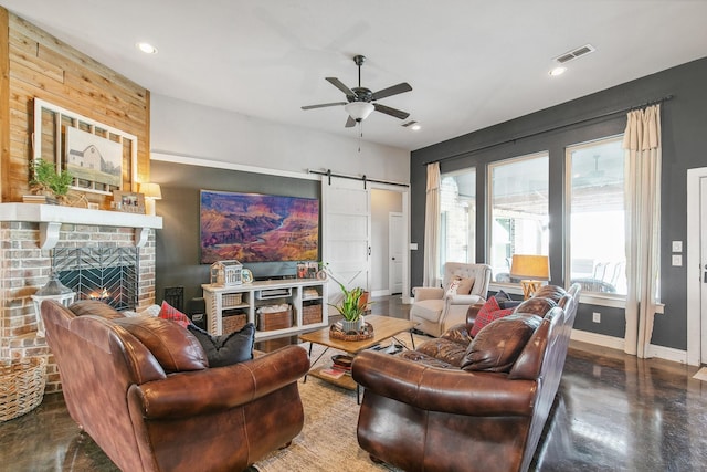 living room with a fireplace, concrete floors, a barn door, and ceiling fan