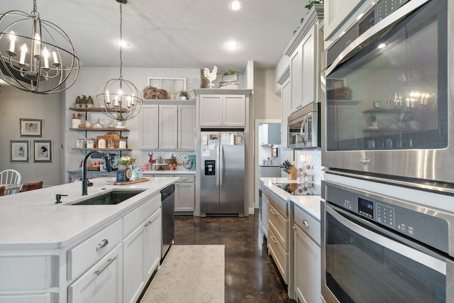 kitchen with sink, stainless steel appliances, a notable chandelier, an island with sink, and pendant lighting