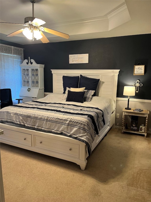 carpeted bedroom featuring a tray ceiling, ceiling fan, and ornamental molding