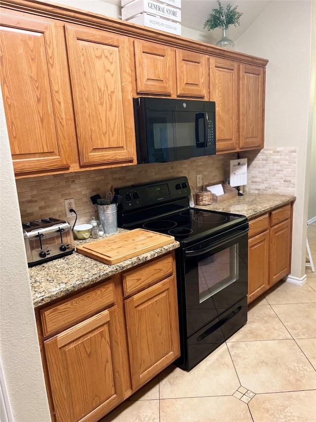 kitchen featuring tasteful backsplash, light stone countertops, light tile patterned floors, and black appliances