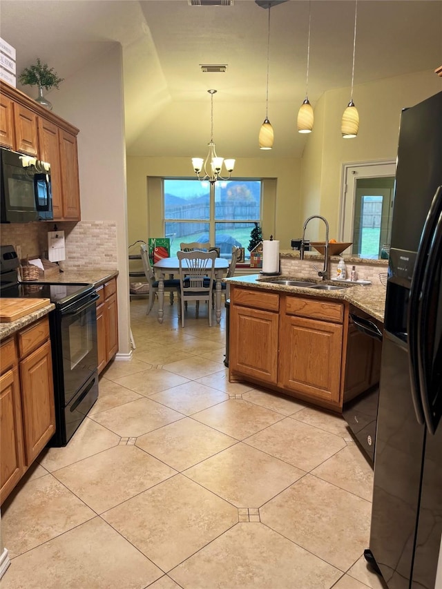 kitchen featuring black appliances, sink, hanging light fixtures, and vaulted ceiling