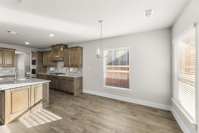 kitchen with premium range hood, visible vents, appliances with stainless steel finishes, and a sink