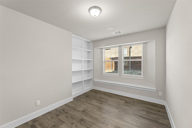 unfurnished room featuring baseboards, visible vents, and dark wood-style flooring