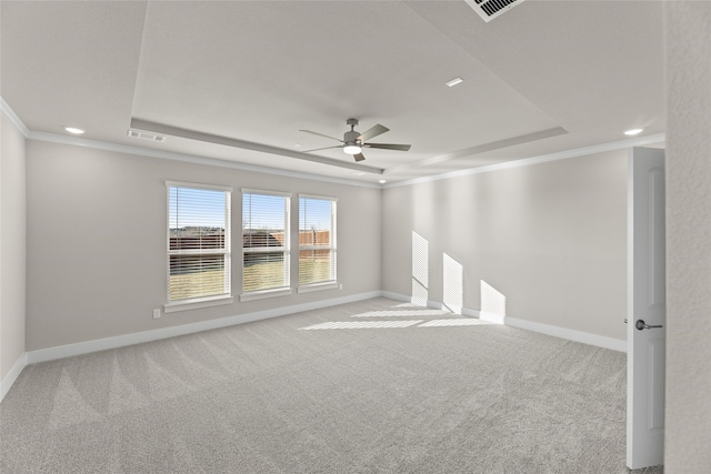 carpeted spare room with a tray ceiling, crown molding, and baseboards