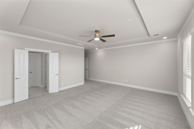 empty room with a healthy amount of sunlight, visible vents, a raised ceiling, and light colored carpet