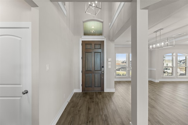 foyer with a notable chandelier, visible vents, baseboards, and dark wood-style flooring