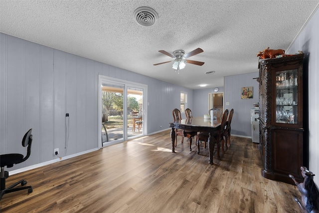 dining area with ceiling fan, wood-type flooring, and a textured ceiling