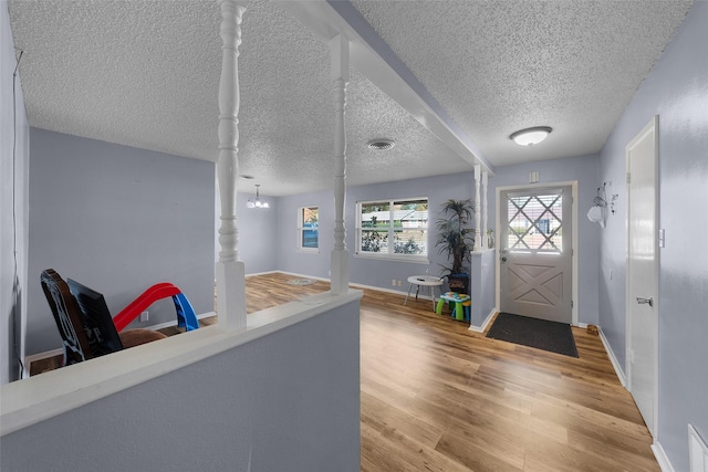 foyer entrance featuring light hardwood / wood-style floors, a textured ceiling, and an inviting chandelier