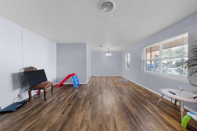 sitting room featuring a textured ceiling, an inviting chandelier, and dark wood-type flooring