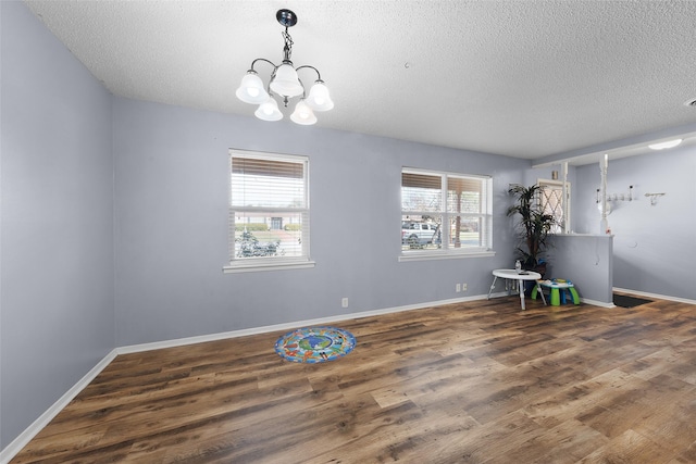 miscellaneous room with dark hardwood / wood-style flooring, a textured ceiling, and a notable chandelier