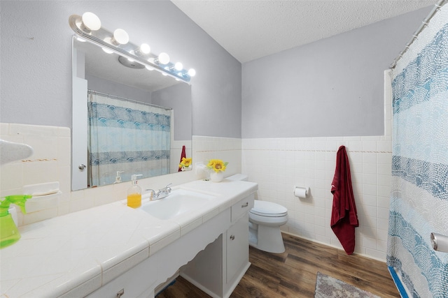 bathroom with vanity, a textured ceiling, wood-type flooring, tile walls, and toilet