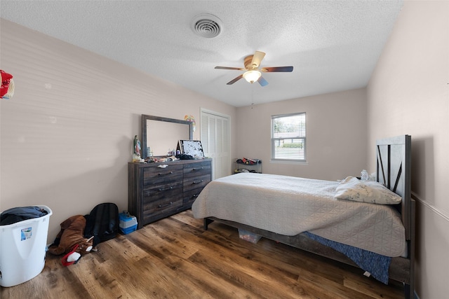 bedroom with hardwood / wood-style floors, a textured ceiling, a closet, and ceiling fan