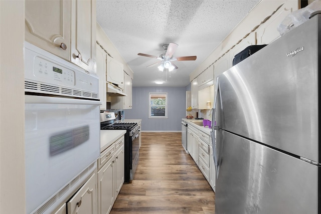 kitchen featuring white cabinetry, ceiling fan, stainless steel appliances, dark wood-type flooring, and a textured ceiling