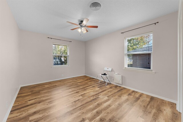 empty room featuring ceiling fan, a textured ceiling, and light hardwood / wood-style flooring