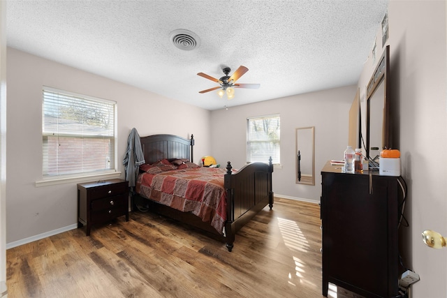 bedroom featuring ceiling fan, wood-type flooring, and a textured ceiling