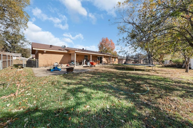 back of house featuring a lawn, a trampoline, and a patio