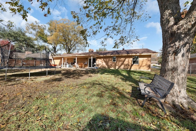 back of house with a yard and a trampoline