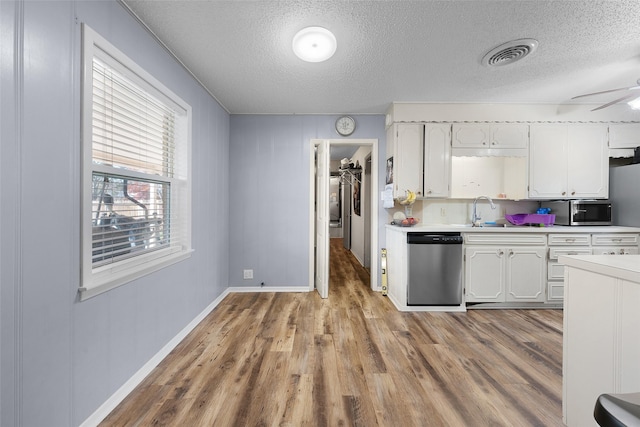 kitchen with a textured ceiling, stainless steel appliances, sink, light hardwood / wood-style flooring, and white cabinets