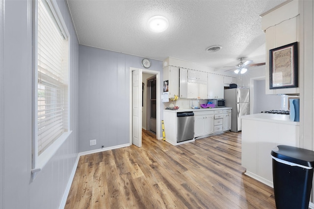 kitchen featuring a textured ceiling, stainless steel appliances, ceiling fan, white cabinets, and light hardwood / wood-style floors