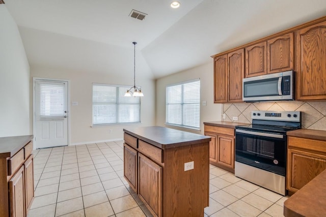 kitchen with a healthy amount of sunlight, a kitchen island, stainless steel appliances, and lofted ceiling