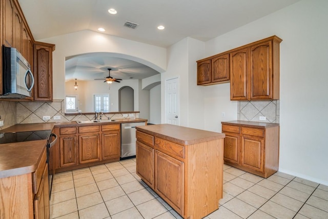 kitchen with a center island, sink, ceiling fan, light tile patterned flooring, and stainless steel appliances