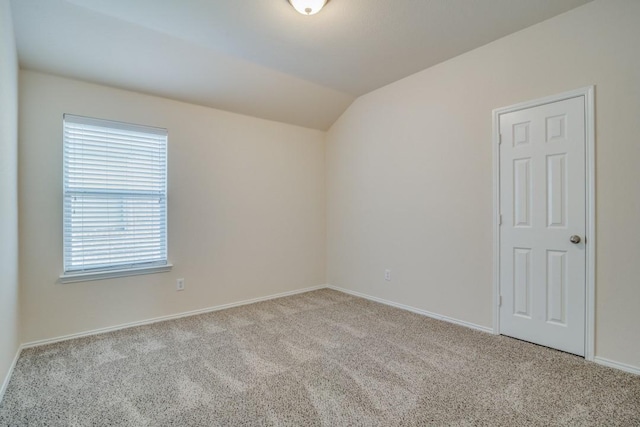 carpeted empty room with lofted ceiling