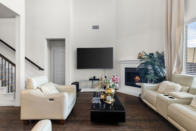 living room with a towering ceiling and dark hardwood / wood-style floors