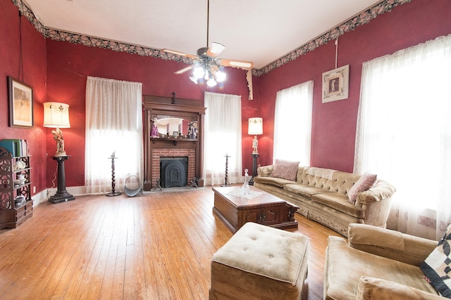 living room with ceiling fan, a fireplace, and light wood-type flooring