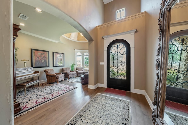 entrance foyer with crown molding, a towering ceiling, and dark hardwood / wood-style floors