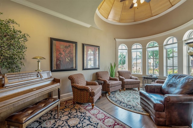 living area with ornamental molding, wood-type flooring, and ceiling fan