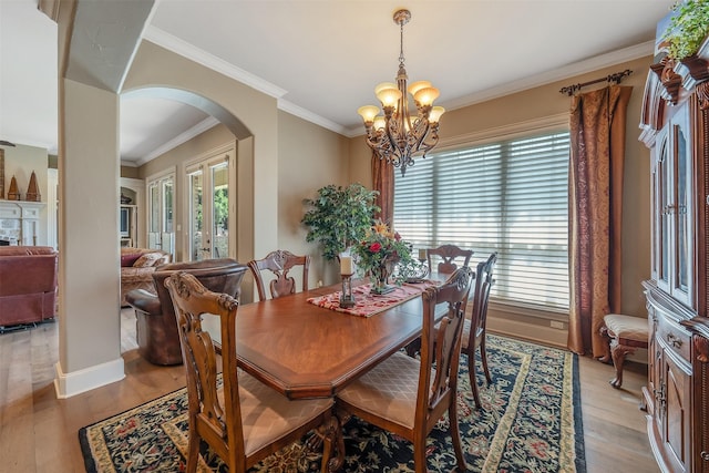 dining space featuring ornamental molding, a chandelier, and light wood-type flooring