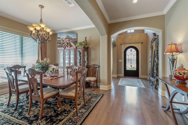 dining space with ornamental molding, a chandelier, and hardwood / wood-style floors