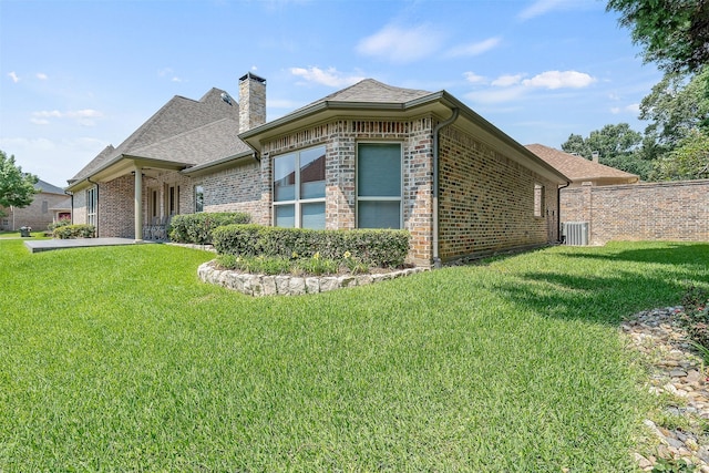 view of side of home with central AC and a lawn