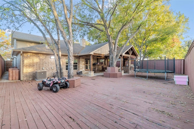 wooden deck featuring a trampoline and central AC unit