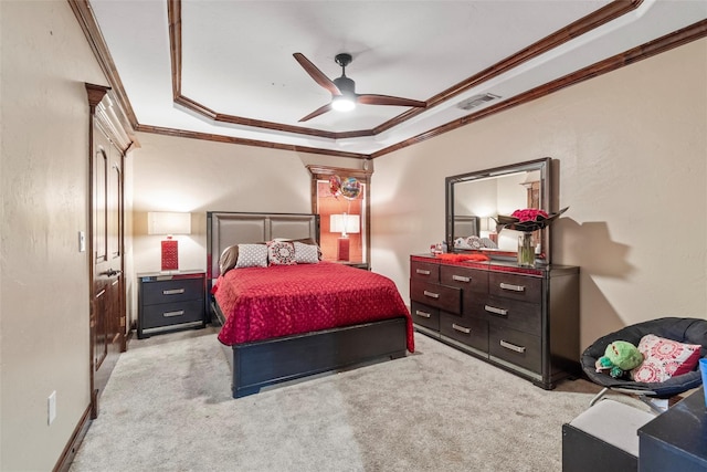 carpeted bedroom with ceiling fan, crown molding, and a tray ceiling