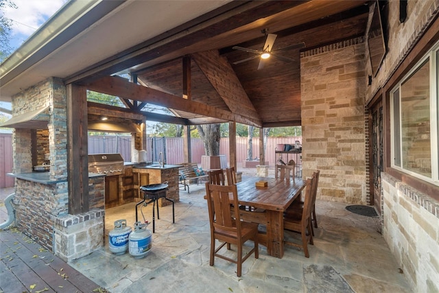 view of patio featuring area for grilling, outdoor dining space, fence, a sink, and exterior kitchen