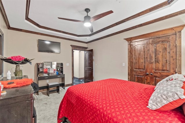 carpeted bedroom with a tray ceiling, ceiling fan, and ornamental molding