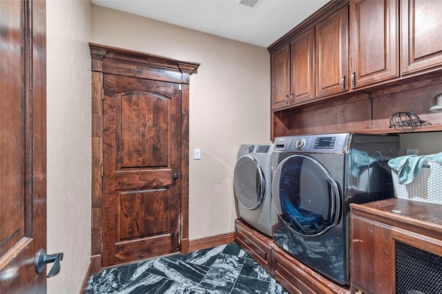 clothes washing area featuring cabinets and washing machine and clothes dryer