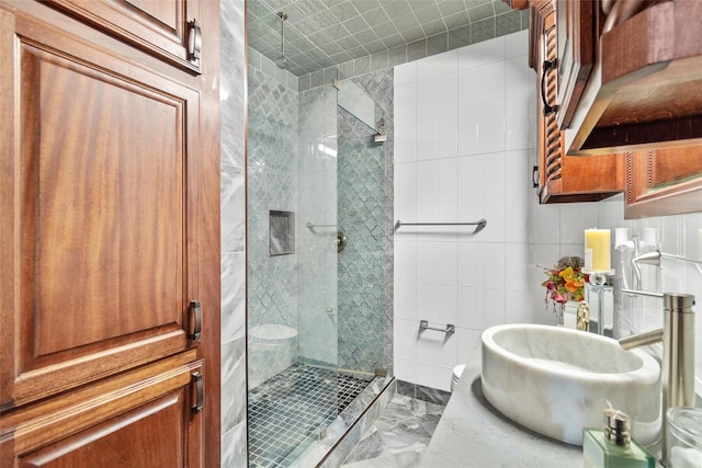 bathroom featuring a tile shower, toilet, tile walls, and sink