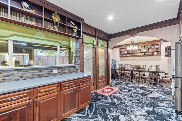 kitchen with an inviting chandelier, ornamental molding, hanging light fixtures, and tasteful backsplash