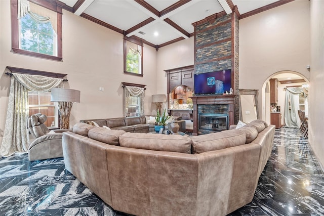 living room with ornamental molding, coffered ceiling, a large fireplace, beamed ceiling, and a high ceiling